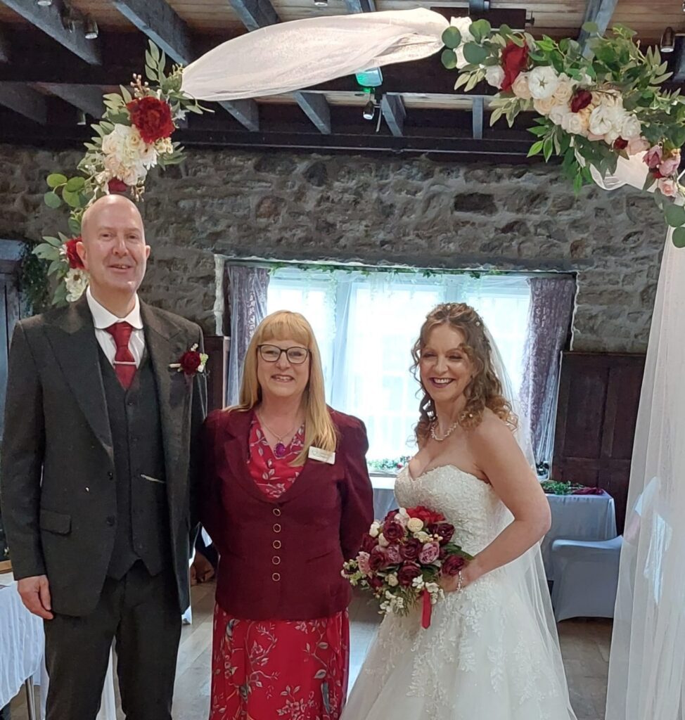 A wedding celebrant from PC Roadshows standing with a joyful newlywed couple after their personalized ceremony, smiling and celebrating their special day.